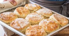 freshly baked biscuits in a pan on a wooden table with a person holding a mitt