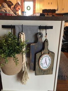 two potted plants are hanging from hooks on the wall next to a cutting board