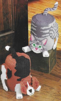 two knitted cats sitting next to each other on the floor in front of a door