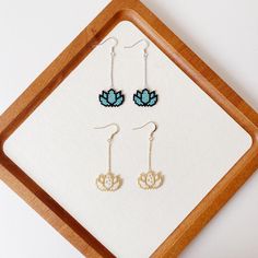 three pairs of earrings sitting on top of a wooden tray next to a white wall