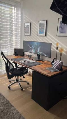 a computer desk with two monitors and a laptop on it in front of a window