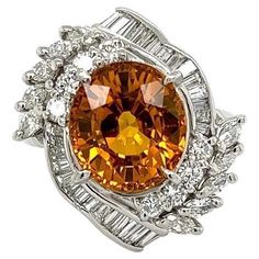 an orange and white diamond ring on a white background with the center stone surrounded by smaller diamonds