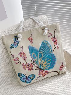 a handbag with blue butterflies on it sitting on a chair next to a window