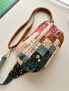 a small patchwork purse sitting on top of a white table next to a computer mouse