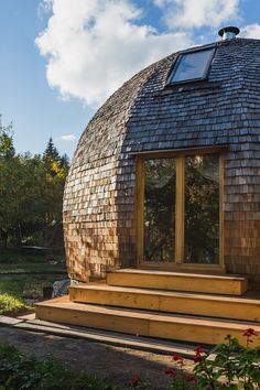 a round wooden building sitting on top of a lush green field