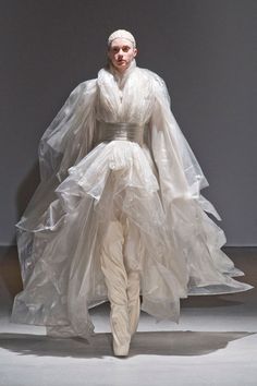 a woman is walking down the runway in a white dress with long veils on her head