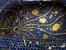 a blue and gold mosaic sink with golden circles on the bottom, in front of a white background