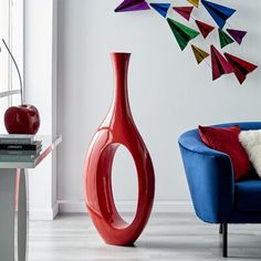 a red vase sitting on top of a table next to a blue chair