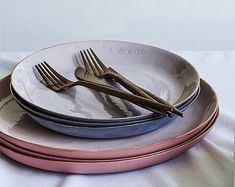 there are three plates with forks on top of each other, one is pink and the other is blue