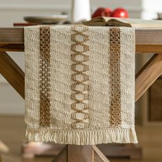 a wooden table topped with a white and brown blanket on top of a wooden table