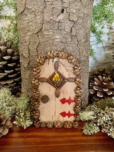 a tree stump with a small house made out of wood and pine cones around it