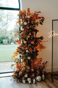 an arrangement of flowers and candles in front of a window with the word autumn written on it