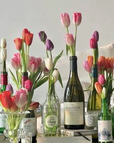 several bottles and vases with flowers in them on a table next to a couch