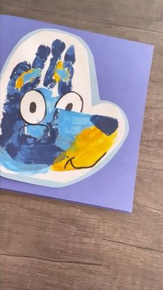 a child's handprinted blue bird with yellow beak