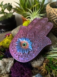 a purple bird with an eye on it's wing sitting on some rocks and plants