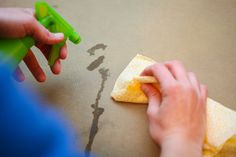 a person is using a sponge to clean the surface of a piece of paper with a green sprayer on it