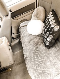 the back seat of a car with two pillows and a pillow on top of it