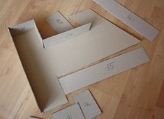 an open cardboard box sitting on top of a wooden floor next to cut out numbers