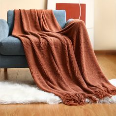 a couch with a blanket on top of it next to a white sheepskin rug