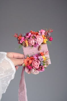 a person holding a pink box with flowers on it