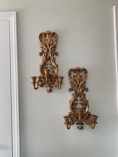 two ornate gold wall sconces on a white wall