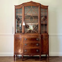 an antique china cabinet with glass doors on the top and bottom, in a living room