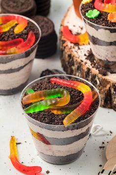 three desserts with different colored candy worms in them