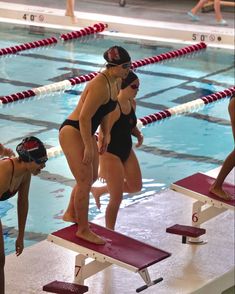 two women in swimsuits standing at the edge of a swimming pool while others watch