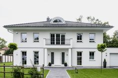 a large white house sitting on top of a lush green field