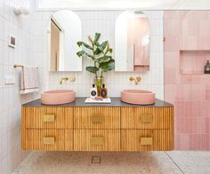 a bathroom with two sinks, mirrors and a plant in the middle of the room