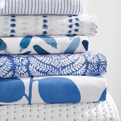 a stack of blue and white bedding on top of each other in different patterns