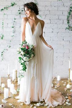 a woman in a white dress standing next to candles and greenery on the floor