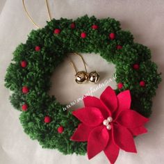 a green wreath with red poinsettia and bells