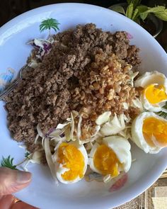 a white plate topped with meat and eggs