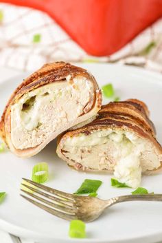 two pieces of chicken and cheese stuffed roll on a white plate with a fork next to it