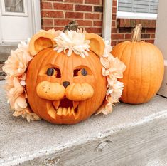 two pumpkins that have been carved to look like lions with flowers on their heads