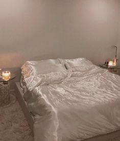 a white bed sitting in a bedroom next to a night stand with candles on it