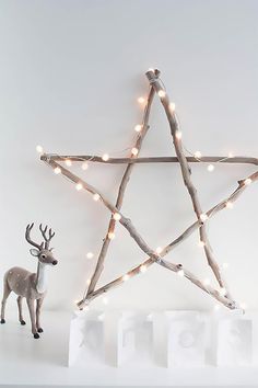 a wooden star with lights on it next to two small white blocks and a deer figurine