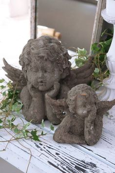 two little angel figurines sitting next to each other on top of a table