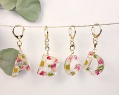 four charms hanging from a clothes line with flowers and letters on them that spell out abc