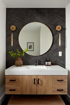 a bathroom vanity with a round mirror above it and two wooden handles on the wall