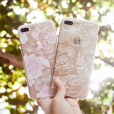 someone holding up two iphone cases with flowers on them in front of the sun shining through some trees