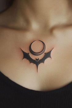 a woman's chest with a bat and crescent tattoo on her left side breast