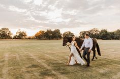 a bride and groom walking with their horse in the field at sunset or sunrise time