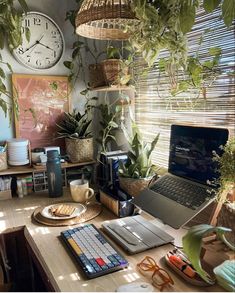 a laptop computer sitting on top of a wooden desk next to a plant filled wall