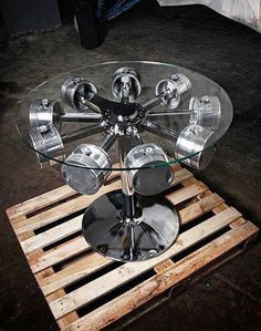 a round glass table with metal parts on wooden pallets