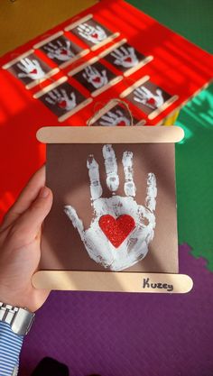 a person holding up a handprint with a heart on it