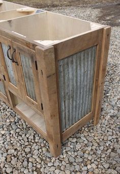 a wooden cabinet sitting on top of a gravel covered ground