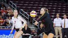 two women are playing volleyball on the court