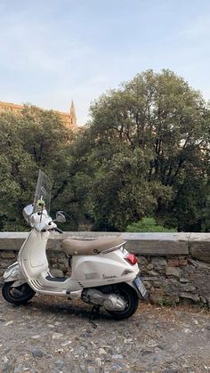 a white scooter parked next to a stone wall